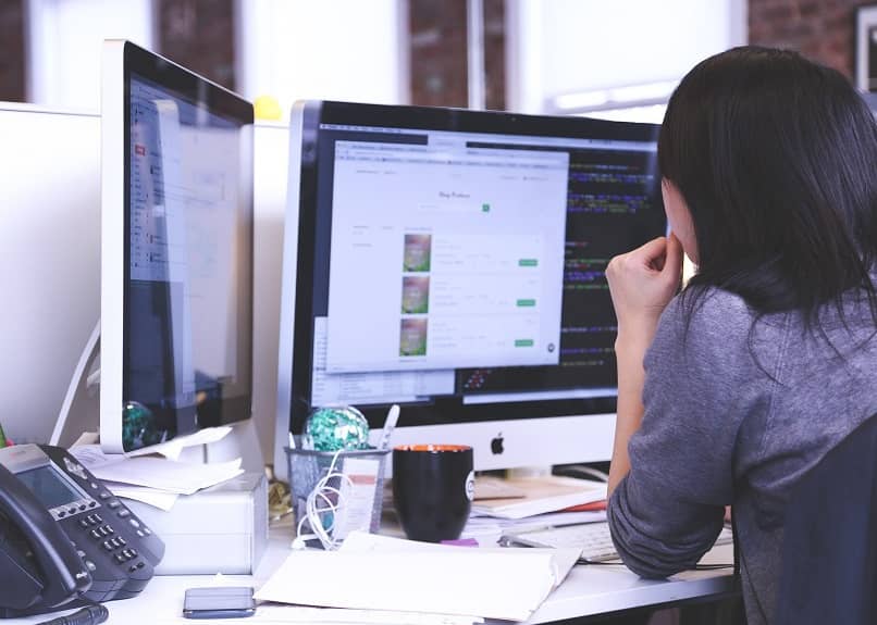 Mujer mirando dos computadoras