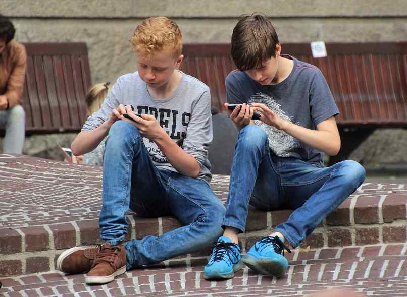 Los jóvenes se sientan y juegan en la calle.